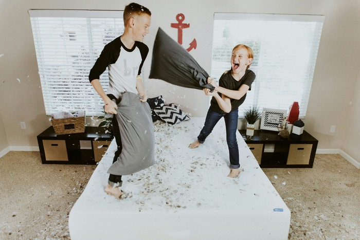 A little boy and a girl playing in the bedroom