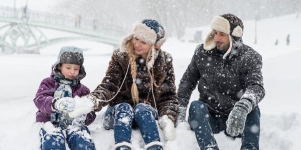 Family Enjoying Snowfall in a Winter Park