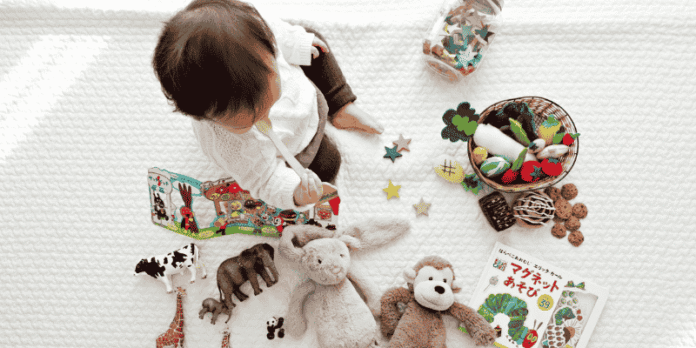 Baby Playing with Toys, Books, and Plush Animals on a White Blanket