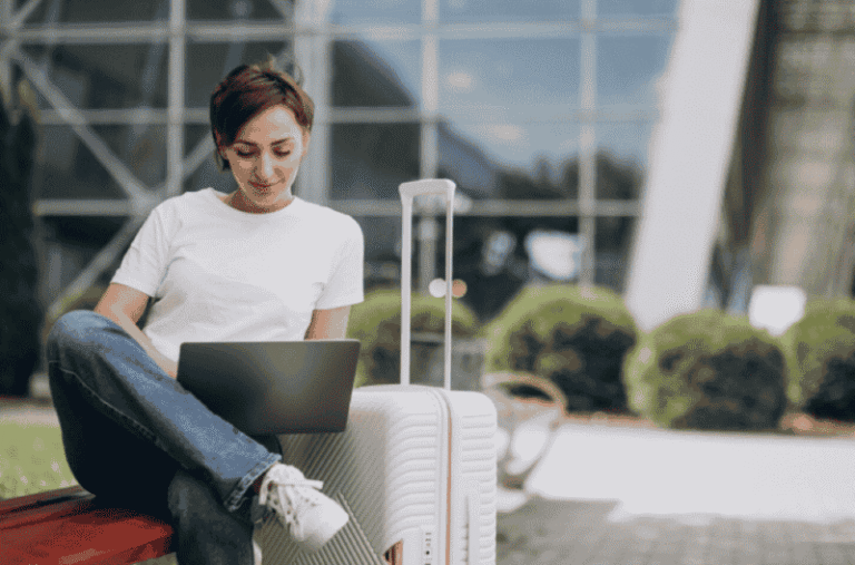 Young Traveler Working on Laptop Beside Trolley Bag at Airport