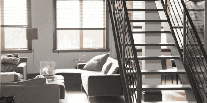 Modern Condo Interior with Stylish Living Room Design A condo living room with modern furniture, natural lighting, and an open staircase design that enhances the space.