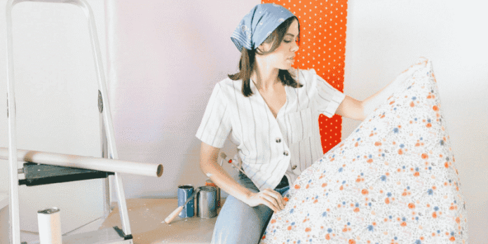 Planning home upgrades with ease and confidence Woman holding decorative wallpaper while preparing for home improvement project with paint cans and ladder in the background