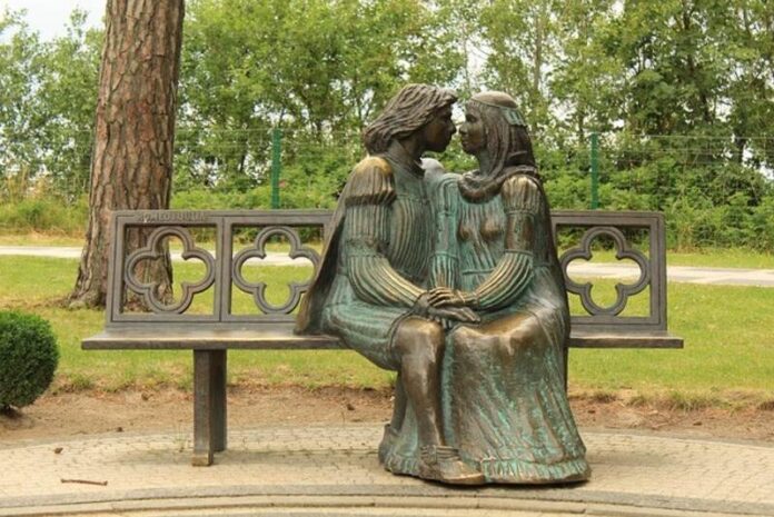 Bronze statue of Romeo and Juliet sitting closely on a bench, symbolizing love and destiny.