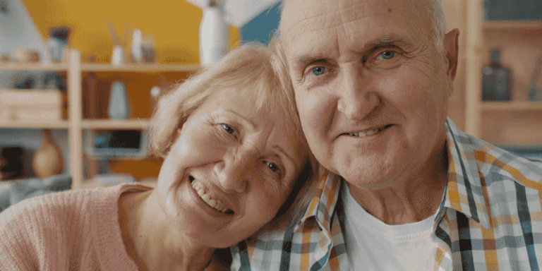 Happy elderly couple smiling together at home, symbolizing love, support, and the decision to consider aged care services.