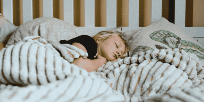 Toddler sleeping soundly in bed under a soft blanket