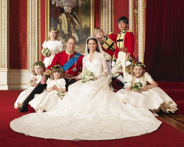 British Royal Family Wedding with Bridesmaids and Page Boys A British royal bride and groom posing with bridesmaids and page boys inside a grand palace room during their wedding ceremony.
