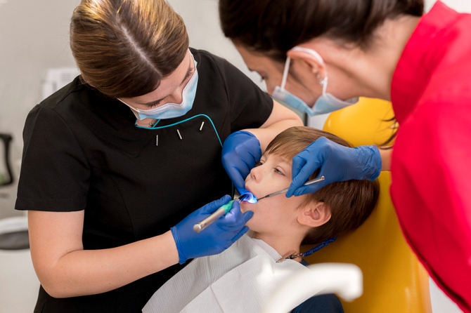 Pediatric Dentist Providing Dental Treatment to a Child Pediatric Dentist Providing Dental Treatment to a Child