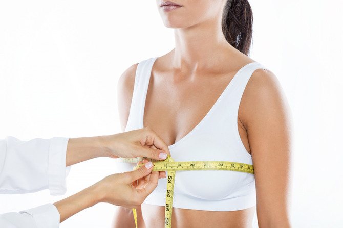 Close up of a plastic surgeon taking precise chest measurements with a yellow tape measure during a breast reduction consultation