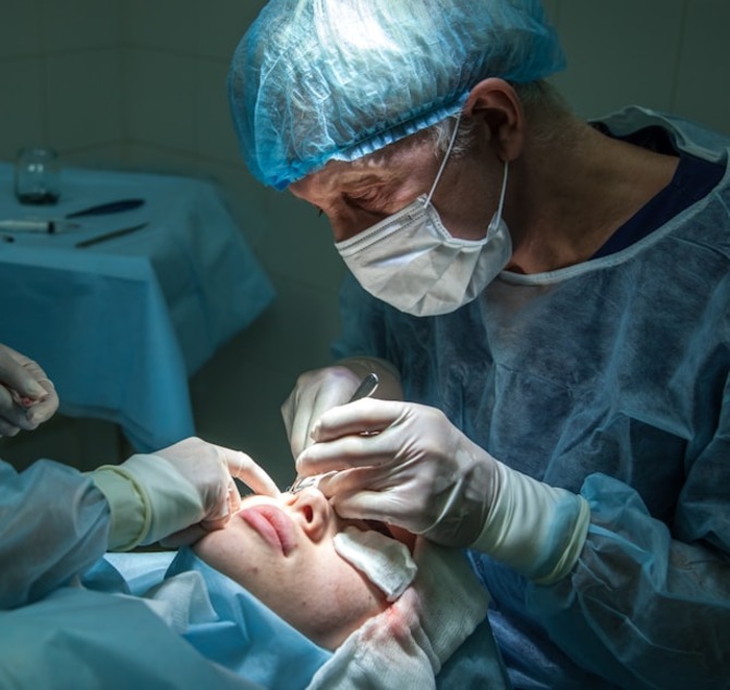 Surgeon in a sterile operating room performing eyelid surgery to correct sagging eyelids caused by aging