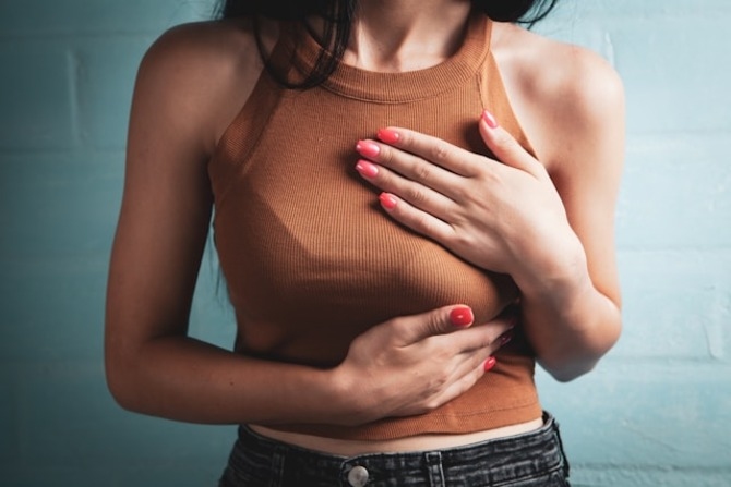 Understanding the Breast Augmentation Journey Beyond Surgery Woman holding her chest area, representing the physical and emotional aspects involved in the breast augmentation process and recovery.
