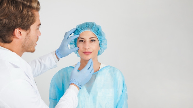 Plastic surgeon examining a patient’s face during a consultation, highlighting natural-looking facial plastic surgery and subtle aesthetic enhancement.