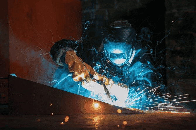 Professional Welder Working on Industrial Welding Project With Safety Helmet and Gloves Professional Welder Working on Industrial Welding Project With Safety Helmet and Gloves